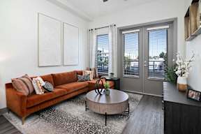 A living room with a brown couch, a round table, and a rug.