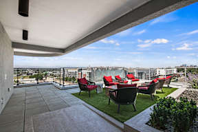 A patio with red chairs and a glass table.