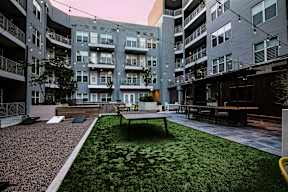 A grassy courtyard with a bench and a table surrounded by apartment buildings.