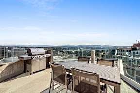 A patio with a table and chairs overlooking a cityscape.