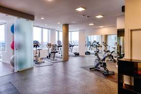 A gym with a variety of exercise equipment including treadmills, stationary bikes, and weights.