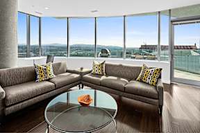 A modern living room with a glass table and two grey couches.