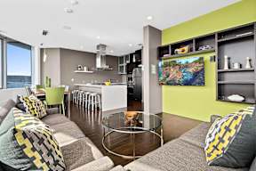 A modern living room with a grey couch and a glass coffee table.