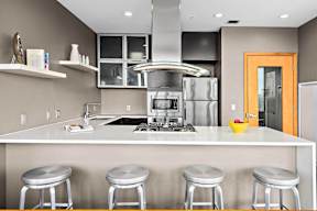 A modern kitchen with a white countertop and stainless steel appliances.