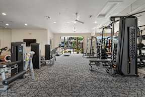 A gym with a variety of equipment including treadmills, weights, and exercise machines.