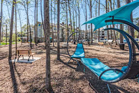 A park with a blue chair and a blue umbrella.