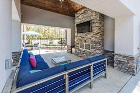 A blue couch is in the middle of a patio with a stone fireplace.