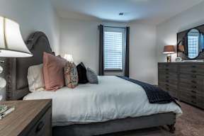 A bedroom with a bed, nightstand, and a lamp.