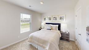 A bedroom with a large bed and a window with blinds.