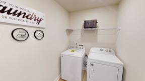 A small laundry room with a sign that says "Check your pockets or consider it a tip".