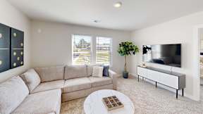 A living room with a grey sofa, a white coffee table, and a television.