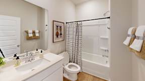 A white bathroom with a toilet, sink, and shower.