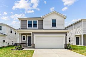 A two-story house with a garage door and a driveway.