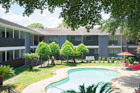 A swimming pool is surrounded by a grassy area and trees.