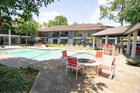 A pool area with chairs and a table.