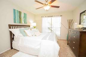 A bedroom with a white bed and a ceiling fan.