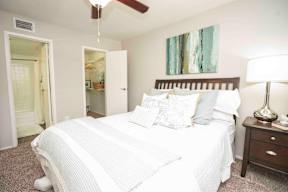 A bedroom with a bed, nightstand, and a painting on the wall.