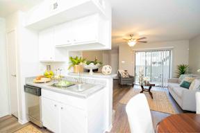 A modern kitchen with white cabinets and a dining area with a white couch.