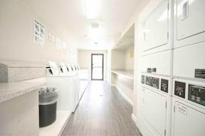 A clean, well-lit commercial kitchen with white appliances and a trash bin.