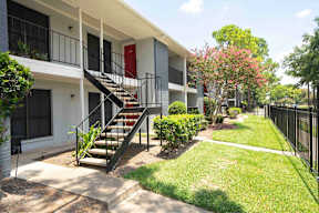A white building with a red door and a black metal railing.