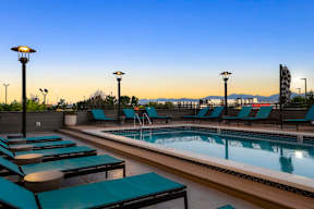 A pool with loungers and lights on the side.