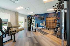 A gym with a variety of equipment including a rowing machine, a leg press machine, and a cable machine.
