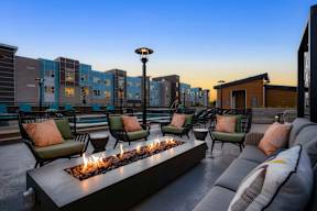 A modern outdoor seating area with a fire pit and comfortable seating.