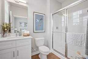 A white bathroom with a toilet, sink, and shower.