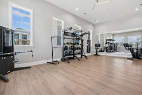 A spacious home gym with wooden floors and a variety of exercise equipment.