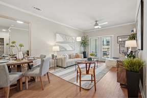 A well-lit, modern living room with a dining area and a large mirror on the wall.
