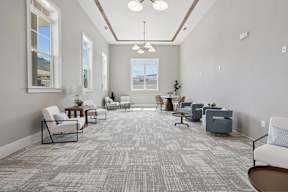 A spacious waiting room with grey carpeting and multiple seating options.