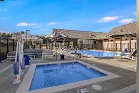 A large outdoor swimming pool with a small pool in the middle and a building in the background.