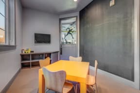 Kids room located in fitness center with small table and chairs, cubby, tv, chalk-wall, and toys