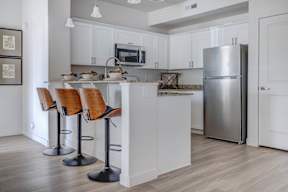A kitchen with a white counter and bar stools.