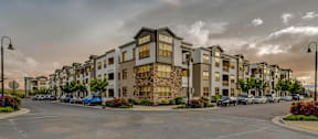 A row of modern apartment buildings with cars parked in front.