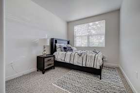 A bedroom with a bed, nightstand, and window.