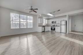 A spacious kitchen and living room with wooden floors and white walls.