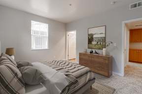 A bedroom with a bed, nightstand, and a painting on the wall.