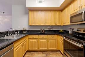 A kitchen with wooden cabinets and black countertops.