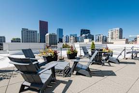 A rooftop patio with chairs and a table with a city skyline in the background.