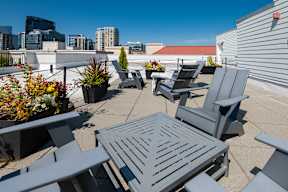A patio with grey furniture and a table surrounded by plants.