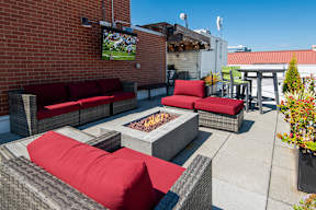 A patio with red cushions and a television showing a football game.