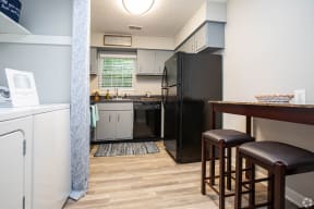 a kitchen with a black refrigerator and a bar with stools