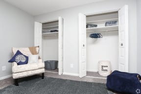 a bedroom with a closet and a chair and a comforter and pillows
