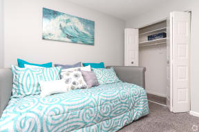 a bedroom with a bed with blue and white pillows and a closet