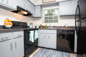 a kitchen with white cabinets and black appliances and a black dishwasher