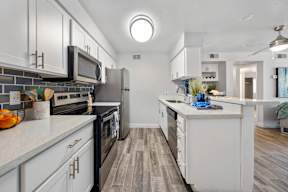 A modern kitchen with white cabinets and a black stove top.