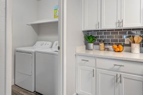 A white dishwasher is in a kitchen with a white shelf above it.