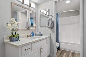 White bathroom with large mirror and white vanity in Station 21 apartments for rent in Mesa, AZ.