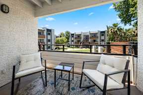 A balcony with two chairs and a table.